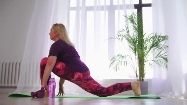 Fitness training - blonde vrouw met overgewicht doet stretching oefeningen voor haar benen — Stockvideo