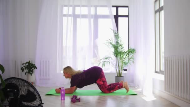 Фитнес-тренировка - блондинка с избыточным весом, занимающаяся фитнес-упражнениями - проведение доски упражнения — стоковое видео