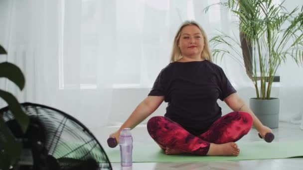 Blond overgewicht vrouw doet fitness oefeningen voor haar handen met behulp van halters — Stockvideo