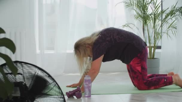 Mujer rubia con sobrepeso haciendo ejercicios para su espalda en la esterilla de yoga — Vídeos de Stock