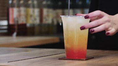 Barmen bardakla bardağın içindeki malzemeleri karıştırıyor.