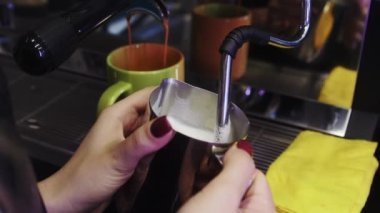 Kahve dükkanı - kadın barista kapuçino için süt köpürüyor buhar çubuğu kullanıyor ve değneği bez kullanarak temizliyor.