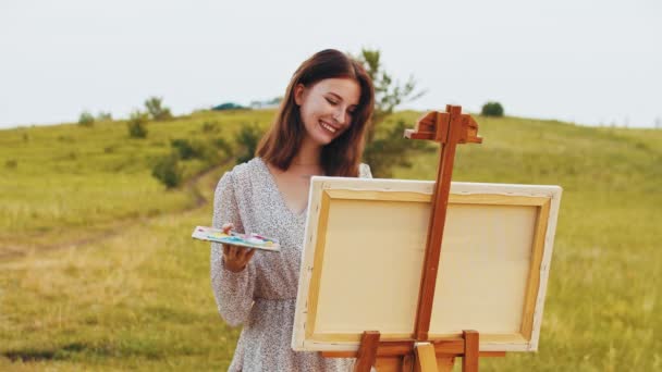 若い笑顔の女性が自然の上に絵を描く — ストック動画