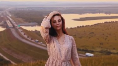 Güzel yüzlü, çilli, günbatımı tarlasında gösteriş yapan genç kızıl bir kadın.