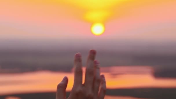 Hand einer jungen Frau, die die Sonnenuntergangssonne berührt — Stockvideo