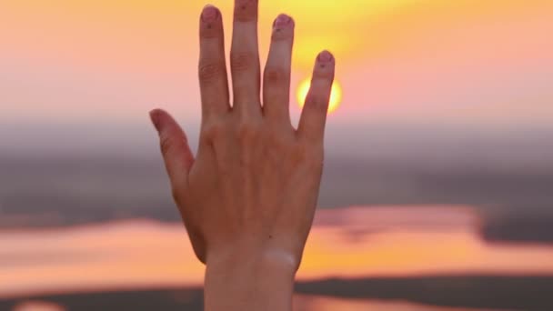 Mano de mujer joven sobre un fondo de cielo al atardecer — Vídeos de Stock