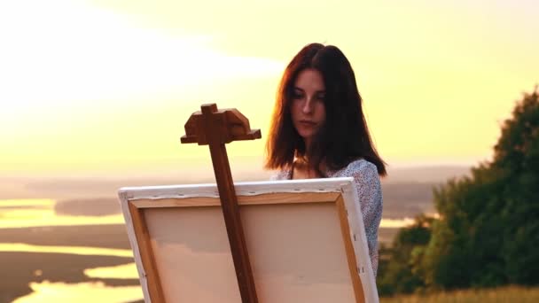 Pintura do lado de fora - jovem bela mulher desenhando uma pintura ao pôr do sol — Vídeo de Stock