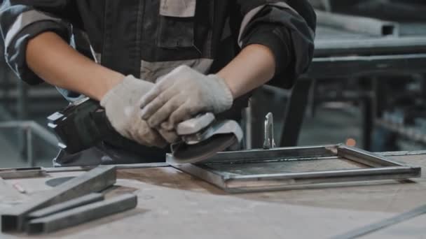 Człowiek pracujący w zakładzie produkcyjnym - szlifowanie konstrukcji metalowej szlifierką kątową — Wideo stockowe