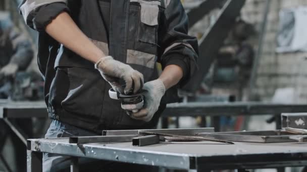 Jonge man met een beschermende bril die in de fabriek werkt - verandert het mondstuk van de haakse slijper — Stockvideo