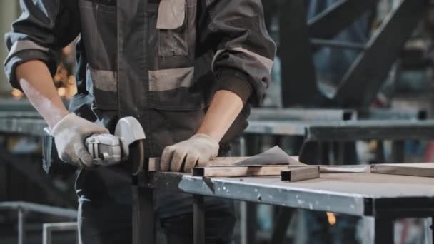 Ung man som arbetar på fabriken - slipning snittet på metall detalj — Stockvideo