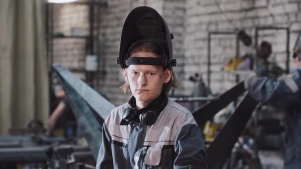 Jeune homme travaillant à l'usine pose le casque de protection et sur le point de commencer à souder les détails — Video