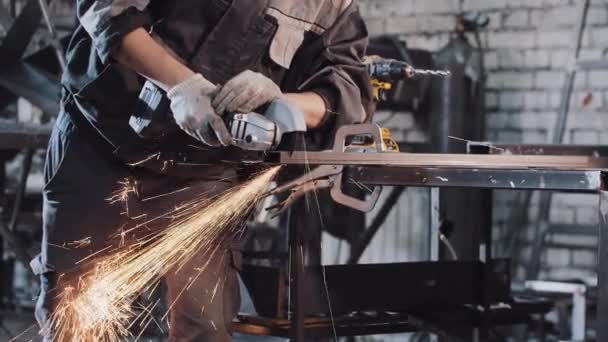 Junger Mann auf der Baustelle - schneidet mit dem Winkelschleifer das Metallstück ab — Stockvideo