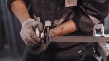 İnşaat fabrikasında çalışan genç bir adam. Metal parçasının açısını öğütüyor.
