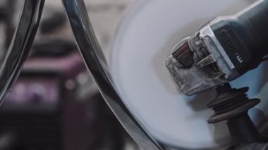 Dairesel metal bir detayı büyük bir açı parlatıcı makinesiyle cilalayan bir işçi.