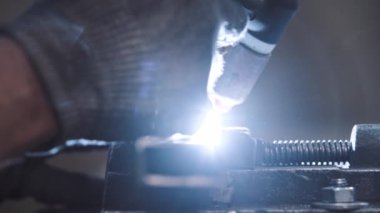 Koruyucu eldivenler giyen bir işçi metal parçalarını kaynaştırıyor.