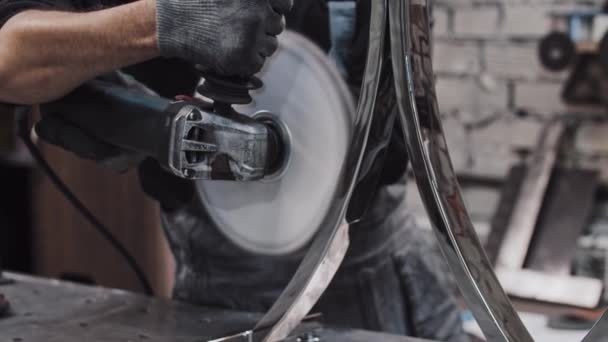 En man arbetare polera en cirkulär metall detalj med en stor cirkelsåg — Stockvideo