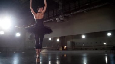 Bale - siyah etekli kadın balerin onu ayna stüdyosunda dans ettiriyor.