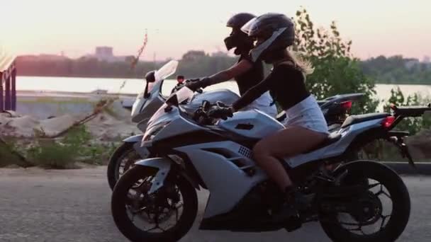 Dos jóvenes montan motocicletas al atardecer. — Vídeos de Stock