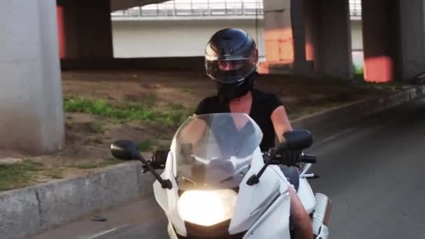 Una mujer en casco protector está montando motocicleta al atardecer — Vídeos de Stock