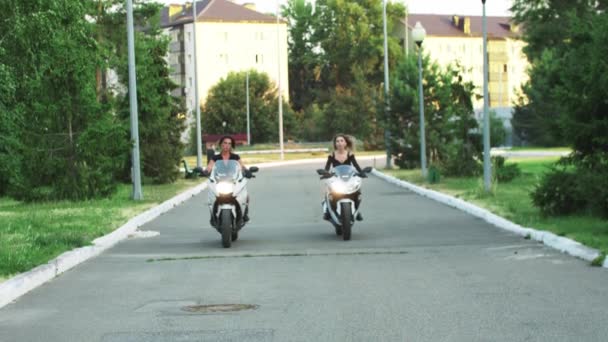 Dos mujeres están montando motocicletas a primera hora de la noche sin cascos — Vídeo de stock