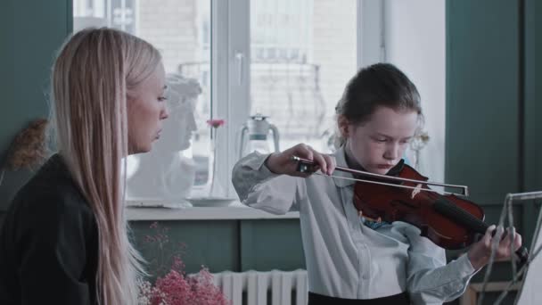 Dívka hrající na housle během lekce s blondýnou učitelkou - říká jí, aby držela luk jinak — Stock video