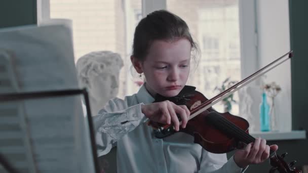 Zmęczony cute girl gry na skrzypcach podczas lekcji przez notatki — Wideo stockowe