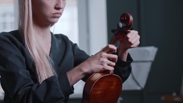 Young blonde woman tuning the violin — Stock Video