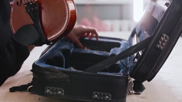 Молодая женщина-музыкант ставит скрипку в футляр — стоковое видео