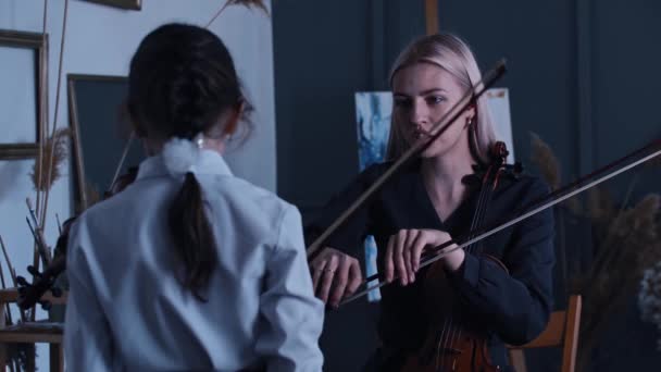 Jeune femme blonde enseignant à une petite fille étudiante comment tenir correctement un arc tout en jouant du violon — Video