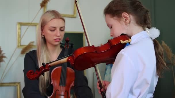 Lección de violín - mujer rubia enseñando a la niña a sostener un violín — Vídeo de stock
