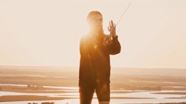 Gün batımında tepede kılıçla antrenman yapan genç bir kadın.