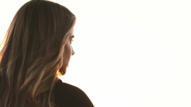 Parlak günbatımında kılıç sallayan uzun saçlı genç bir kadın.