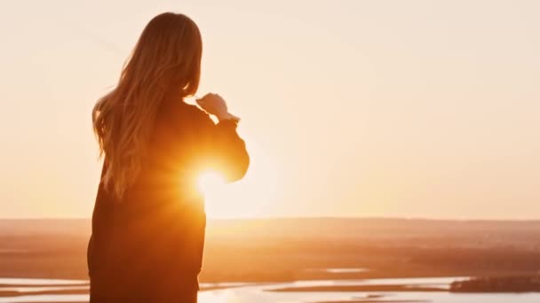 Giovane donna oscillante con una lama sul tramonto arancione brillante e vomitando in aria — Video Stock