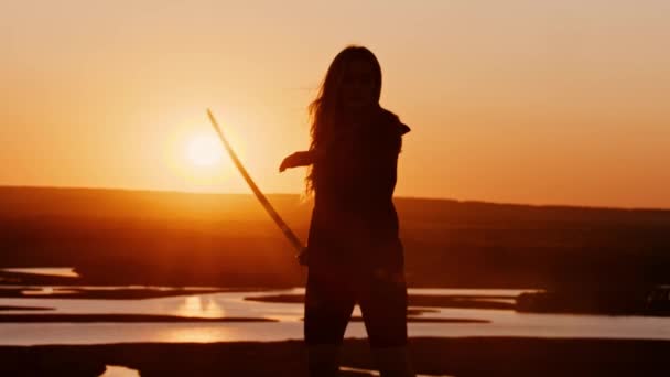 Young woman swinging with a blade on orange sunset — Stock Video