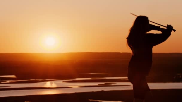 Mujer joven balanceándose con una hoja al atardecer naranja tardío — Vídeo de stock