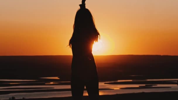 Young woman in a hoodie swinging with a blade on late orange sunset — Stock Video