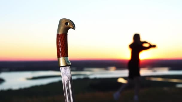 Обучение мечей - молодая женщина, тренирующаяся на природе на закате - ручка меча на переднем плане — стоковое видео