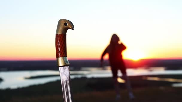 Trening mieczy - młoda kobieta trenuje na przyrodzie podczas zachodu słońca i idzie do uchwytu miecza na pierwszym planie — Wideo stockowe