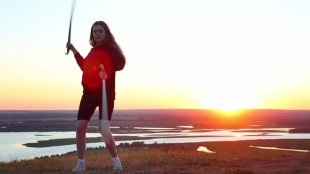 Swords training - young woman training with two swords on the background of the sunset — Stock Video