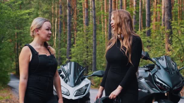 Mujeres amigas de pie cerca de las motos en el bosque y hablando — Vídeo de stock