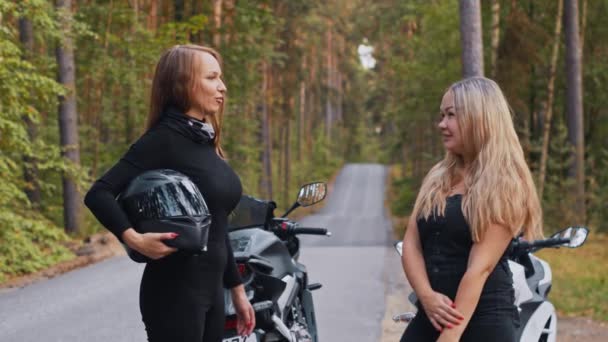 Adult women friends standing near the motorbikes in the forest and talking — Stock Video