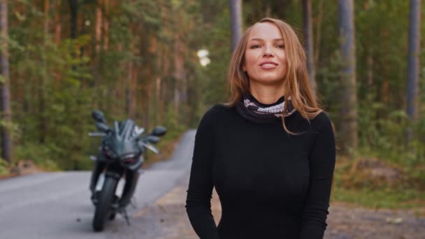 Erwachsene Motorradfahrerin setzt Helm auf und blickt in die Kamera — Stockvideo