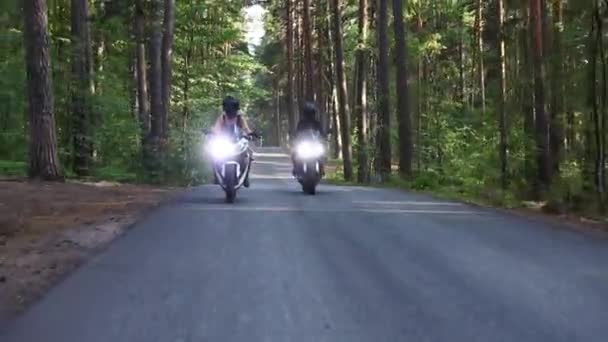 Deux femmes à moto sur la route étroite vide dans la forêt en plein jour — Video