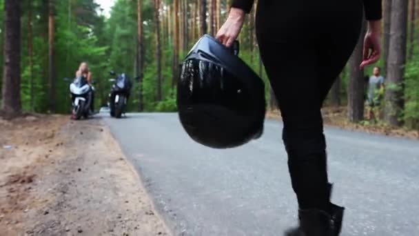 Motorräder im Wald - Frau in schwarzer Kleidung geht mit Motorrad und Helm zu ihrem Freund — Stockvideo
