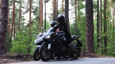 Ormanda motorsikletler - kasklı iki yetişkin kadın ormanda motosikletle gezintiye çıkıyorlar.