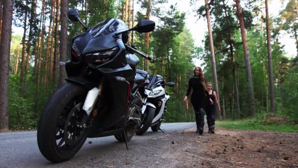 Мотоцикли в лісі - жінка в чорному черепасі сидить на мотоциклі і збирається злетіти з дороги — стокове відео