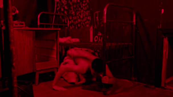 Bláznivý polonahý muž plazí pod postelí v červeném osvětlení — Stock video