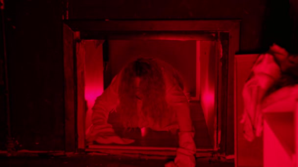 Scary woman in straitjacket crawling in ventilation shaft in red lighting - looking in the camera — Stock Video