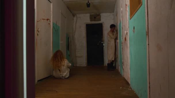 Skräckskådespeleri - man och kvinna i korridorerna till skrämmande jävla mentalsjukhus — Stockvideo