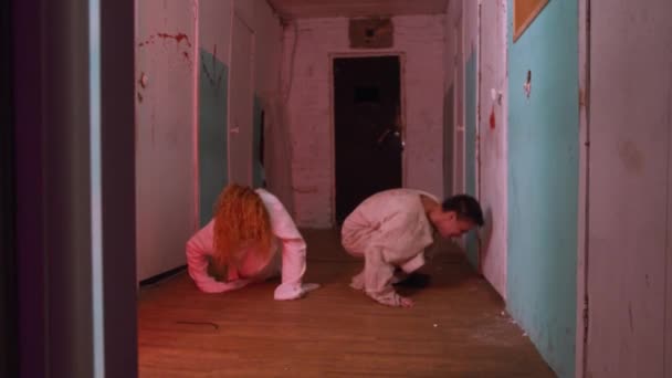 Actuación de terror - hombre y mujer enloqueciendo y arrastrándose por el pasillo de un hospital mental sangriento de miedo a la cámara — Vídeos de Stock
